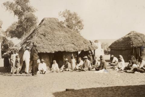 Aboriginal people outside thatched huts 1923
