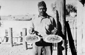 Albert Namatjira holding to painted mulga plaques at Hermannsburg 1939. 